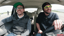 two men are sitting in a car with the word thinkiules on the bottom