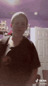 a boy is standing in front of a purple wall and a door with a tiktok watermark