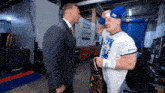 two men are standing next to each other in a room with a sign that says bud light arena on it