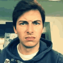 the man is wearing a blue hoodie and making a funny face .
