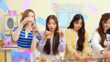 a group of girls are sitting around a table eating cupcakes and candy .