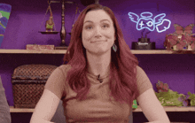 a woman with red hair is smiling in front of a neon sign that says " angels "