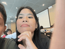 a woman with her hand on her chin looks at the camera in a restaurant