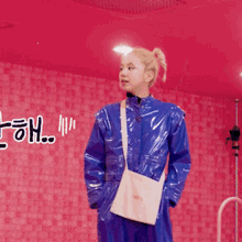 a woman in a blue raincoat is standing in front of a pink wall with the word oh written on it