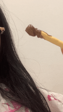 a close up of a person 's hair and a stick with chocolate sauce on it