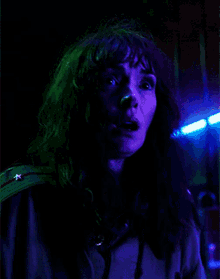 a woman with long hair is standing in a dark room with blue lights behind her .