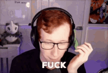 a man wearing headphones and glasses is sitting in front of a computer .