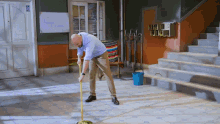 a man cleaning the floor with a mop in front of a white board that says ' a ' on it