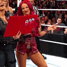 a woman with red hair is holding a sign that says bad on it