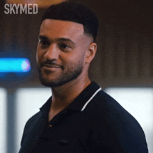 a man with a beard wearing a black shirt with the word skymed on the bottom right