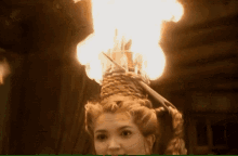 a woman wearing a wicker hat with flames coming out of it