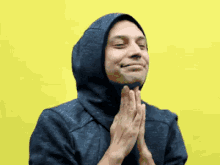 a man wearing a hooded jacket is praying with his hands together