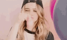 a woman wearing a baseball cap is making a face