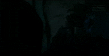 a man is standing in a dark room with a lamp and a window .