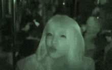 a woman with long blonde hair is standing in a crowded room .
