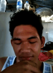 a man with his eyes closed has a bottle of water on his head