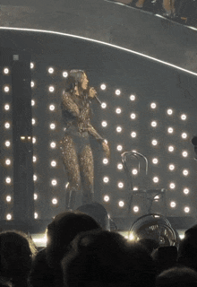 a woman in a leopard print bodysuit sings into a microphone