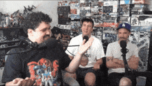 three men are sitting in front of microphones and one of them has a shirt that says friday