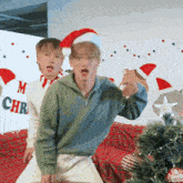 two young men are dancing in front of a christmas tree .