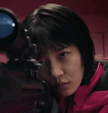 a close up of a woman looking through a sniper scope