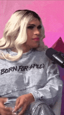 a woman wearing a shirt that says born for speed is sitting in front of a microphone