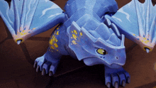 a blue dragon with a green eye is laying down