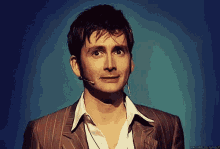 a close up of a man wearing a suit and a microphone with a blue background