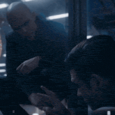 a bald man in a suit is talking to another man