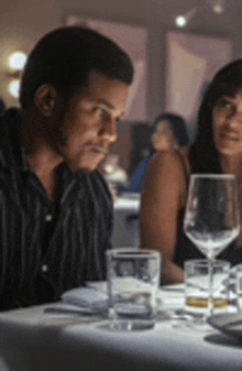 a man and woman are sitting at a table in a restaurant with wine glasses .