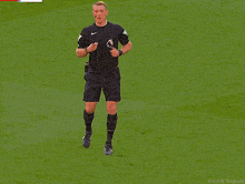 a soccer referee wearing a nike shirt stands on a field