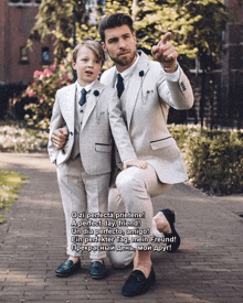 a man in a suit kneeling next to a little boy in a suit