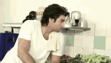 a man is standing in a kitchen with a towel around his neck
