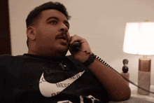 a man wearing a nike shirt is talking on a telephone