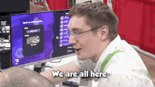 a man sitting in front of a computer with the words we are all here on the bottom