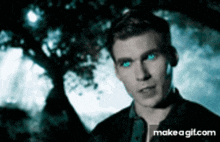 a man with blue eyes is standing under a tree