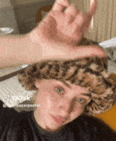 a woman wearing a leopard print hat has a tiktok sticker on her face