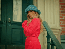 a woman wearing a louis vuitton hat stands in front of a building