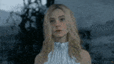 a woman in a white dress is looking at the camera