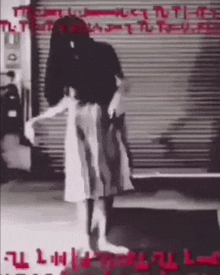 a woman in a white dress is standing in front of a garage door with graffiti on it