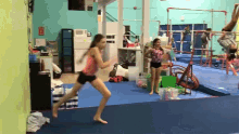 a girl is jumping in a gym with a sign that says fire exit