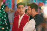 a man in a red suit is standing next to a boy in a white shirt .