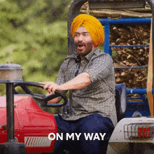 a man in a turban is driving a tractor with the words " on my way " behind him