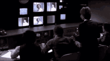 a group of people are sitting in front of a bunch of television screens