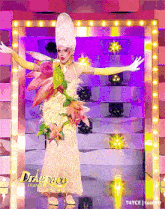 a drag queen is standing on a stage with her arms outstretched in front of a sign that says france all stars