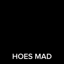 a man in a suit and tie is standing in front of a door and saying hoes mad .