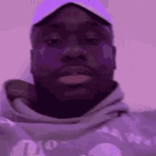 a close up of a man wearing a hat and a purple hoodie .