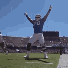 a football player in a blue jersey with the number 76 on it is dancing on the field .