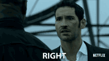 a man in a suit stands in front of a sign that says right netflix