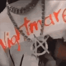 a person wearing a necklace with the word nightmare on it