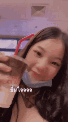 a girl wearing a mask and holding a drink with a straw